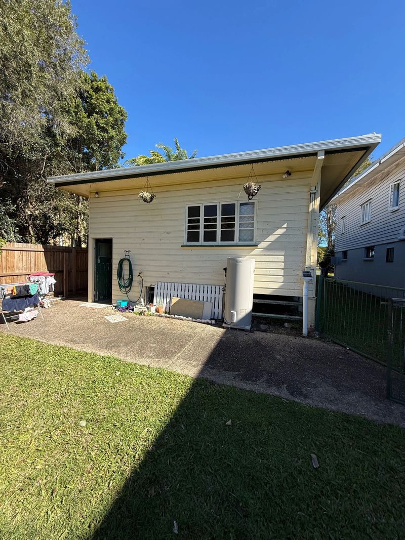 Small backyard shed with gardening tools and a water tank