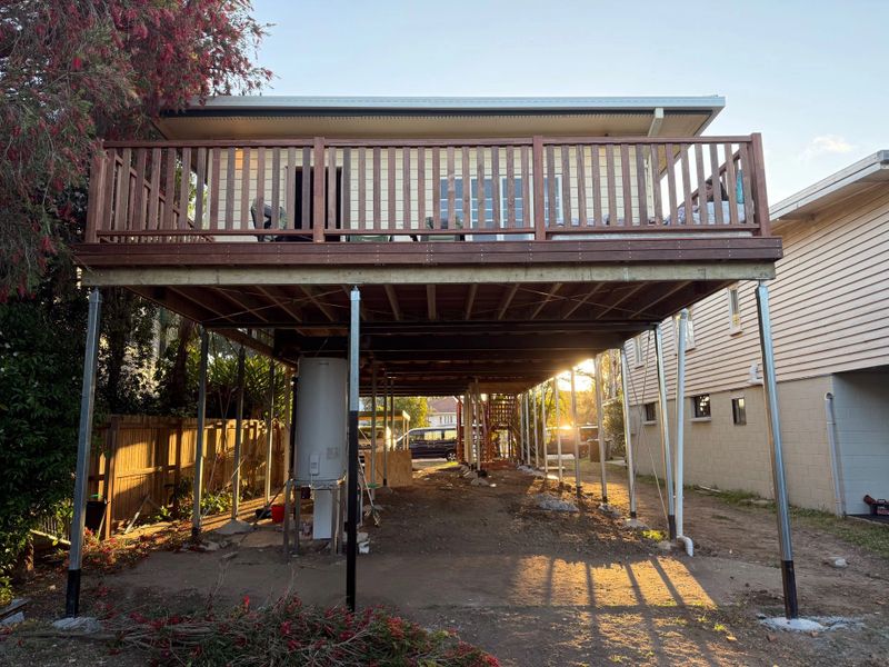 Elevated wooden deck with metal supports in a backyard at sunset
