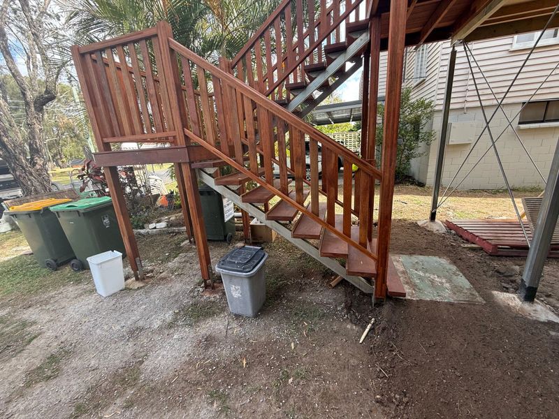 Wooden outdoor staircase with trash bins underneath