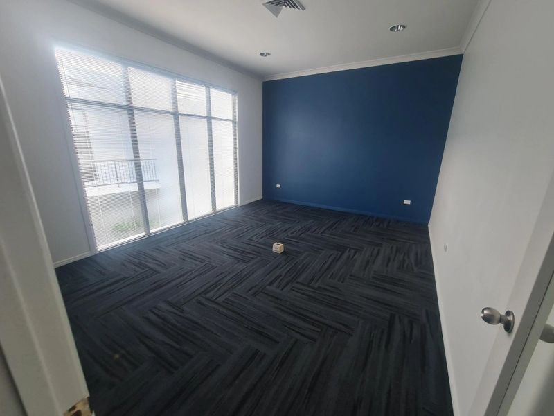 Empty room with large window and dark carpet flooring