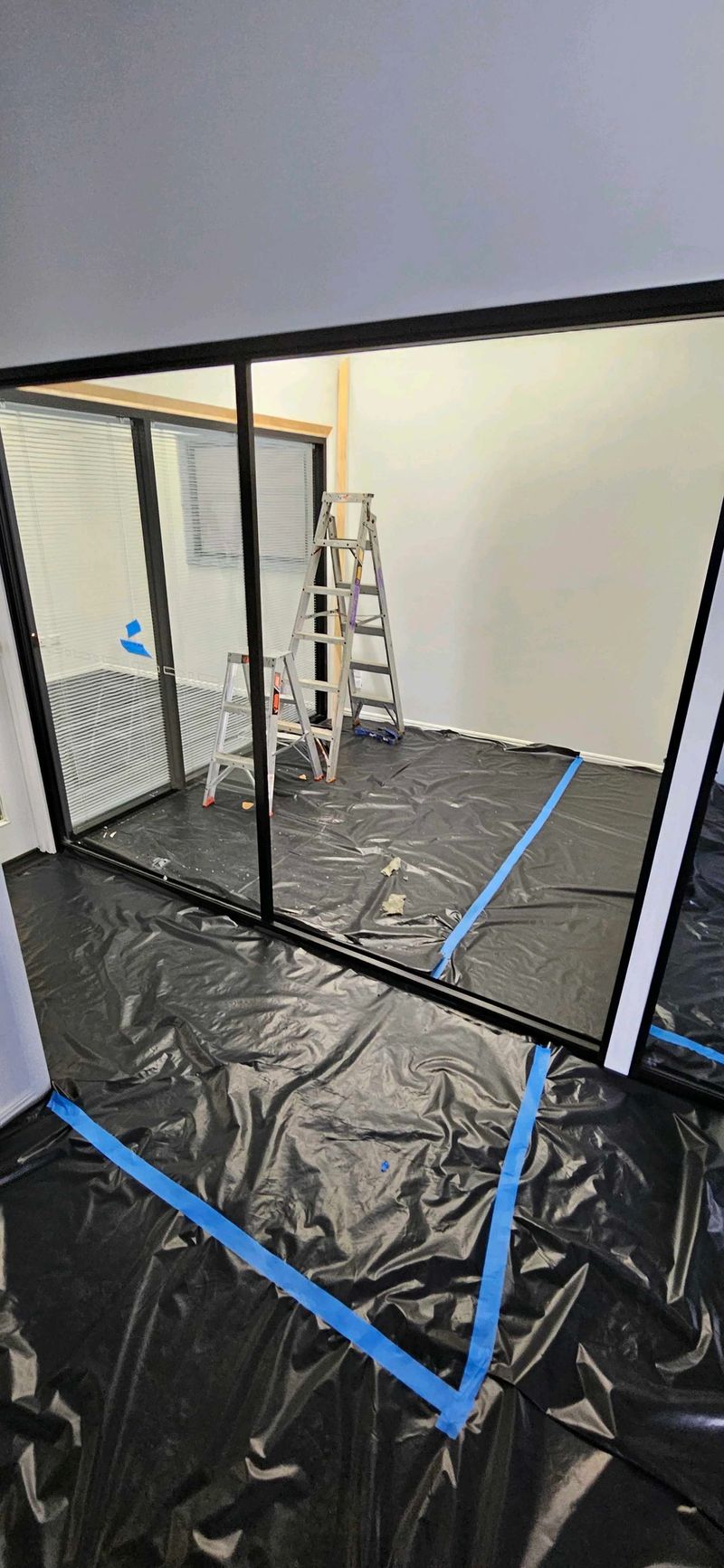 Room under renovation with ladders and protective plastic floor covering