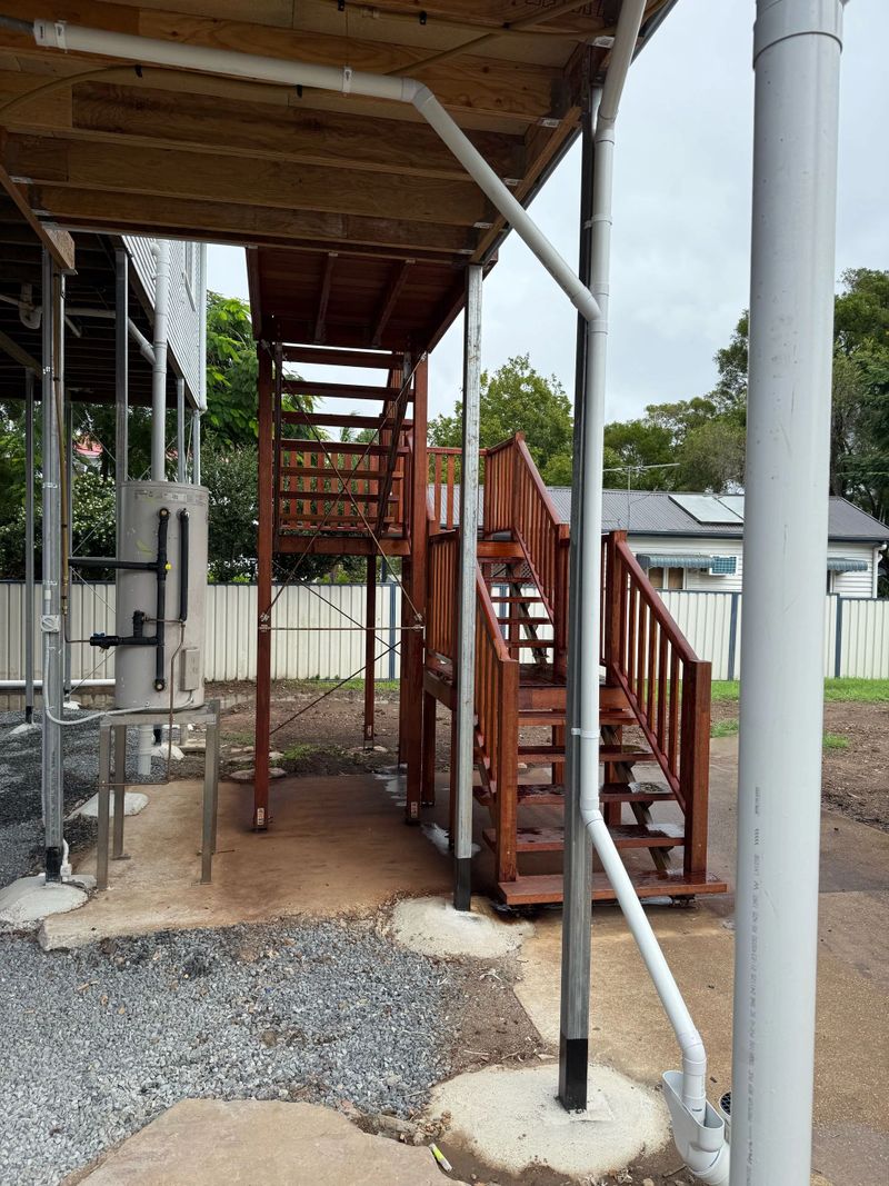 Wooden outdoor staircase with metal railing under a shelter frame