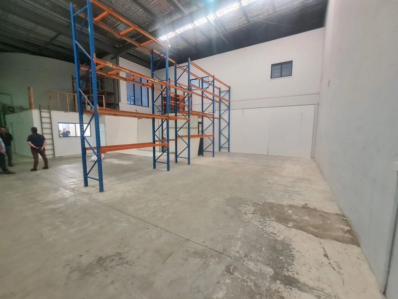 Empty warehouse with blue and orange metal shelving units and concrete floor